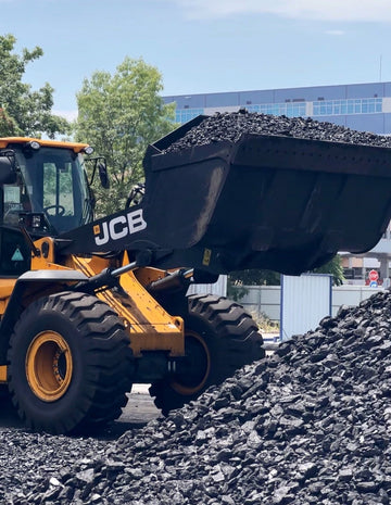 Traktor hebt und lädt hochwertige Anthrazitkohle, bereit für den Transport zur Produktionsanlage.